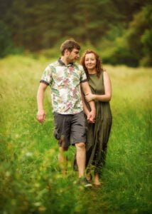 Couple walking hand-in-hand through a grassy meadow during an outdoor family photoshoot in Nottingham.