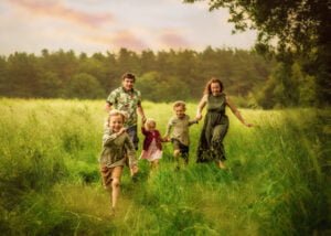 Family running joyfully through a green meadow during an outdoor family photoshoot in Nottingham.