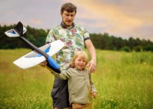 Father and son holding a toy airplane during an outdoor family photoshoot in Nottingham.