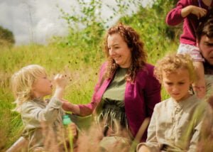 Mother smiling at her son while sitting in a meadow during an outdoor family photoshoot in Nottingham.