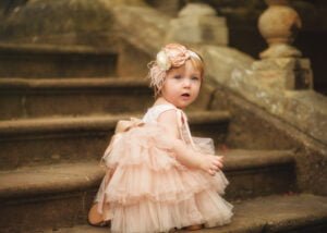 Toddler in a pink tutu dress sitting on stairs during her 1st Birthday Photoshoot in Nottingham.
