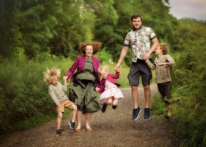A joyful family holding hands and jumping a lush green path in Nottingham, with children's laughter filling the air.