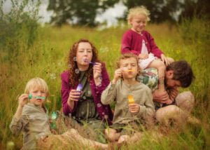 Family blowing bubbles together in a meadow during an outdoor family photoshoot in Nottingham.