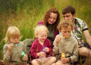 Family sitting in a meadow blowing bubbles during an outdoor family photoshoot in Nottingham.