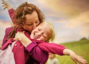 Mother kissing her laughing daughter during an outdoor family photoshoot in Nottingham.