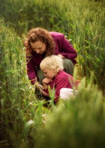 Mother and young daughter exploring a wheat field during an outdoor family photoshoot in Nottingham.