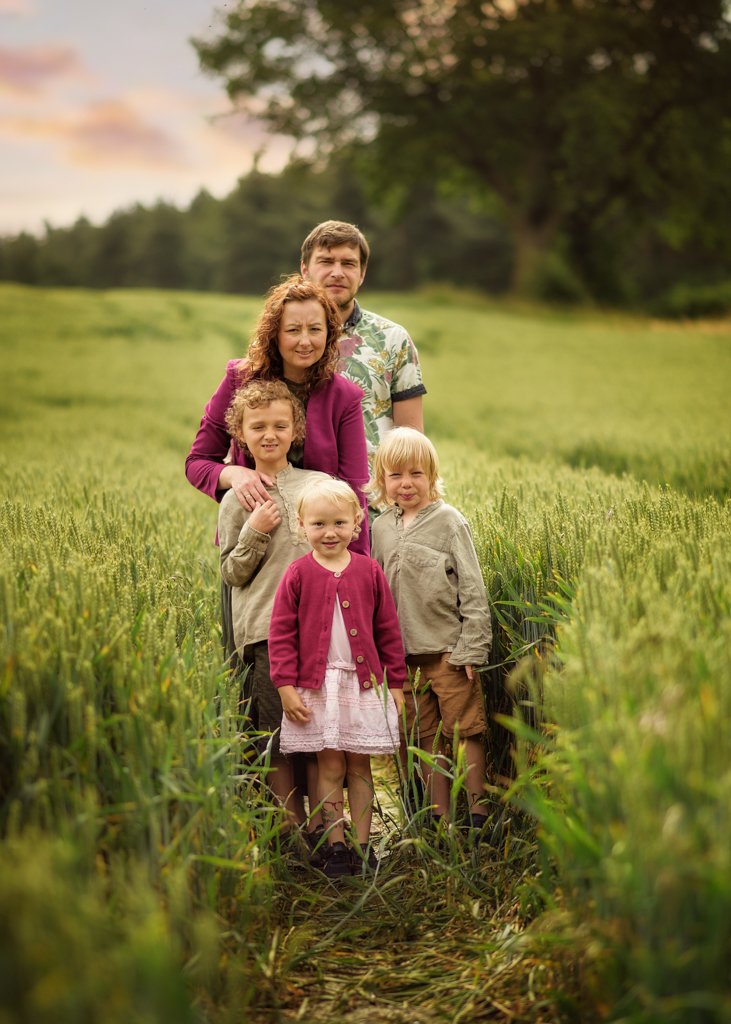 A family stands closely together, surrounded by the vibrant greenery of Nottingham's fields, their faces lit by the gentle dusk light.