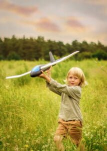 Boy playing with a toy airplane in a green field during an outdoor family photoshoot in Nottingham.