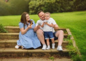 A family of three playing with toys on garden steps during a lighthearted family photoshoot in Nottingham.