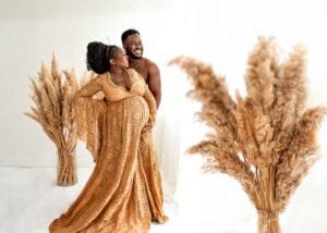 Expectant couple holding the baby bump in a maternity photography session with pampas grass decor.