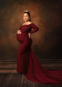 Pregnant woman in a regal maroon gown poses for a maternity photography session in Nottingham.