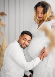 Father-to-be lovingly cradles the baby bump during a studio maternity photoshoot in Nottingham, with the mother-to-be glowing in a lace gown.