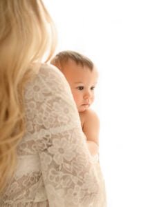 Mother holding her baby, a serene moment captured in soft lighting by an affordable Nottingham photographer.