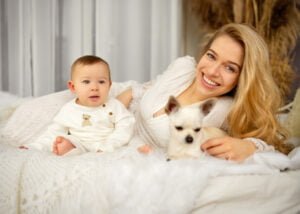 Smiling mother with her baby and small dog during a cozy baby photography session in Nottingham.