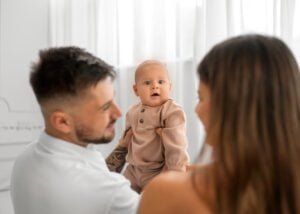 Baby smiling joyfully while parents look on, photographed in Nottingham by a professional family photographer.