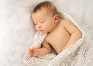 Close-up of a peacefully sleeping baby wrapped in a soft crocheted blanket during a baby photography session.