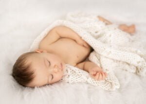 Sleeping baby wrapped in a crocheted blanket during a professional baby photography session.