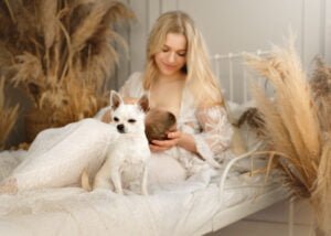 Mother breastfeeding her baby in a boho-inspired baby photography session with a small dog nearby.