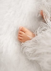 Close-up of baby toes peeking out of a soft blanket during a baby photography session.