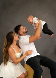 Father lifts baby with mother smiling, captured by a professional family photographer in Nottingham.