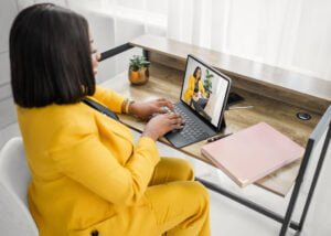 Professional woman in yellow suit typing on a laptop during a business photography session in Nottingham.
