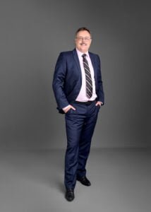 Business photography full-body corporate portrait of a confident businessman in a navy suit.