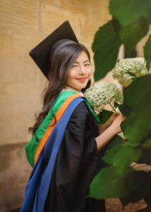 Female graduate in cap and gown smiling with flowers at Nottingham University