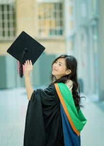 Female graduate holding cap and smiling at Nottingham University