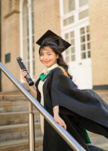 Female graduate holding diploma on stairs at Nottingham University