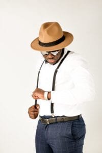 Stylish man in a hat and suspenders adjusting his outfit during a men’s photoshoot in Nottingham.