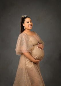 An expectant mother in Nottingham glows in a golden maternity dress, her joy as luminous as the sparkling details of her attire.