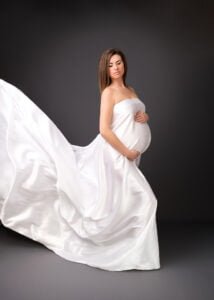 Studio maternity portrait in Nottingham with flowing white gown and dramatic lighting