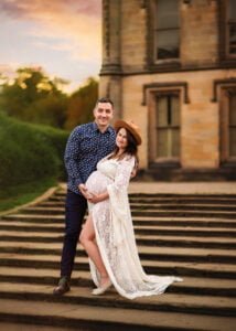 A joyous couple celebrates their maternity journey with a sunset photoshoot on historic steps, embodying the beauty and anticipation of pregnancy.