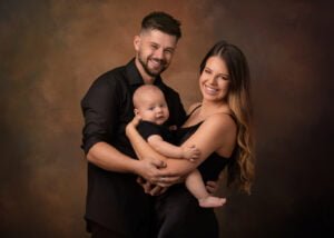 A joyful family portrait by a Nottingham photographer, capturing a moment of love with a young couple holding their baby.