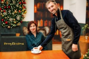 Business photography session of a woman in a café with a barista, set in a cozy Christmas atmosphere.