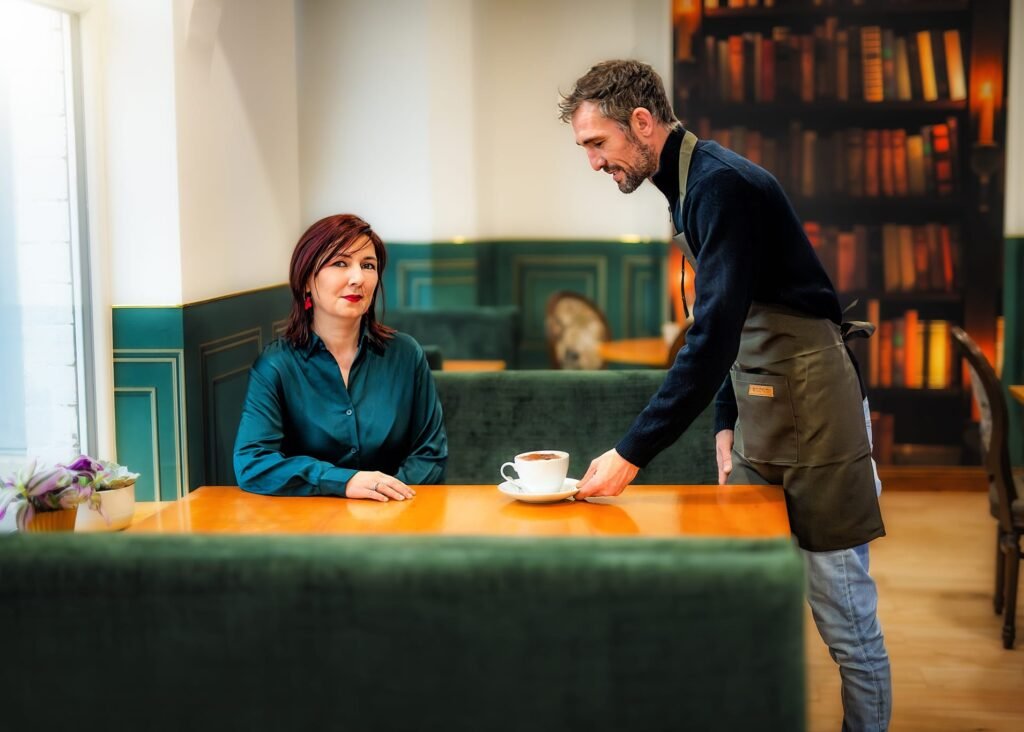 Business photography of a barista serving a cup of coffee to a female customer in a stylish café.