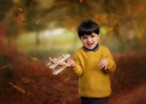 boy playing with a plane during autumn children photography in Wollaton Hall Park Nottingham