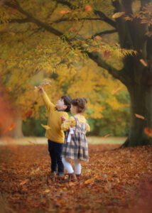 Children playing with autumn leaves, a scene from Eastwood's family photography in Nottingham.
