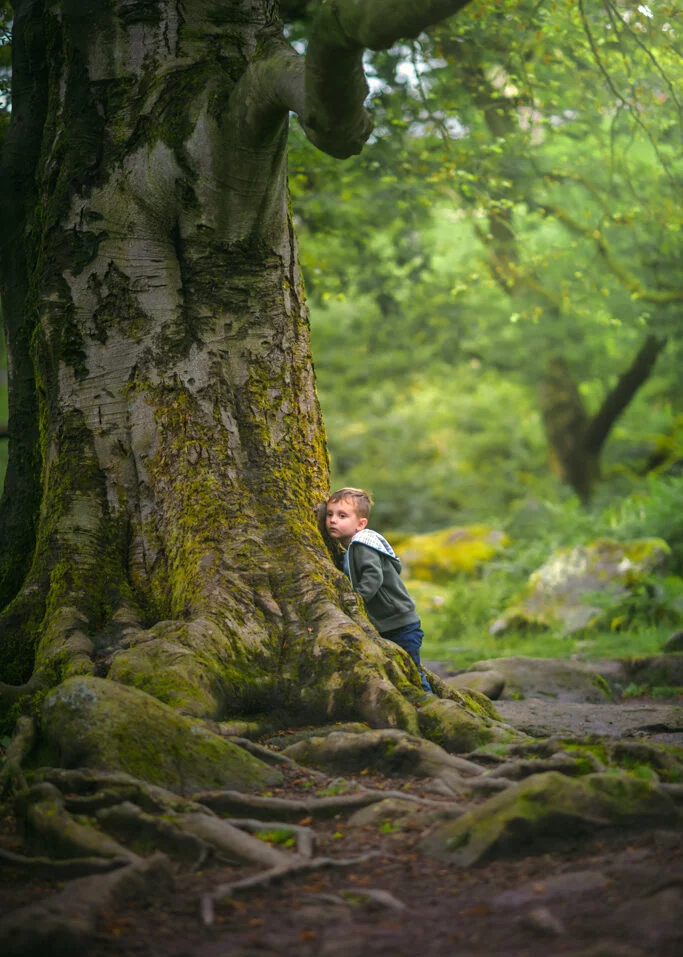Young boy hugging a large tree during an outdoor photoshoot for kids in a Nottingham forest.