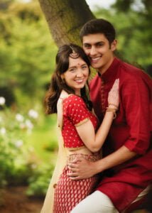 An affectionate couple in traditional Indian attire sharing an intimate moment under a tree.
