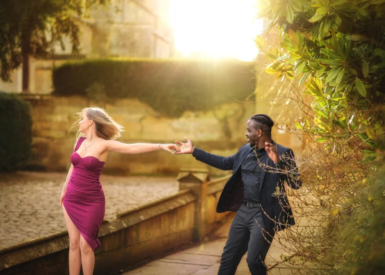 Playful couple in elegant attire dancing in the sunset light in Nottingham, showcasing couple photography.