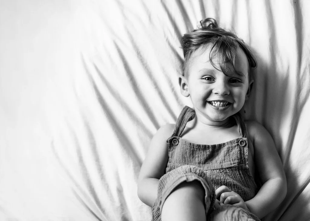 Smiling toddler in a playful moment during a photoshoot for kids.