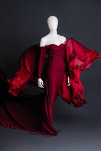 Flowing burgundy maternity photoshoot dress displayed on mannequin with flying fabric