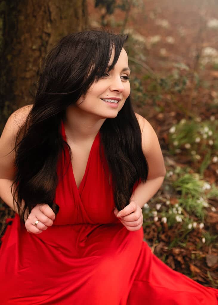 Smiling Woman in Red Dress Surrounded by Snowdrops