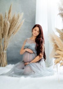 Pregnant woman seated in sheer grey tulle maternity dress during Nottingham photoshoot