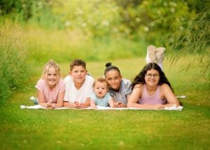 Group of five siblings lying on a blanket smiling during a family photography session