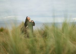 Outdoor Female Portrait Photography – A woman in a black dress embraces the wind, exuding confidence and serenity in Nottingham’s natural landscape.