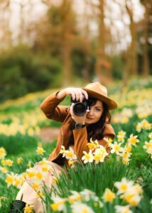 Nottingham Portrait Photographer – A female photographer in a brown jacket captures the beauty of spring among daffodils, celebrating artistry and storytelling.