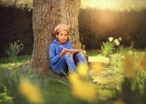 Nottingham Family Photographer - Portrait of a boy wearing a beret, writing in a diary, surrounded by blooming daffodils during a family outdoor photoshoot at Elvaston Castle in spring