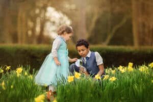 Nottingham Family Photographer - Siblings playing with a magnifying glass amidst blooming daffodils at Elvaston Castle during a spring outdoor photoshoot